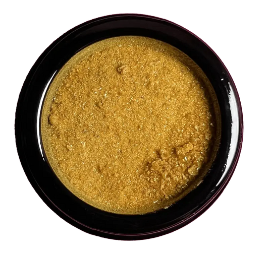 Golden-yellow powder in a dark circular container.