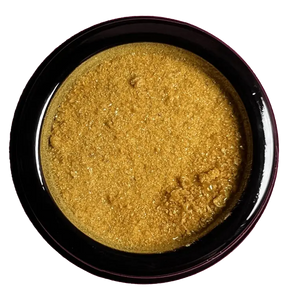 Golden-yellow powder in a dark circular container.